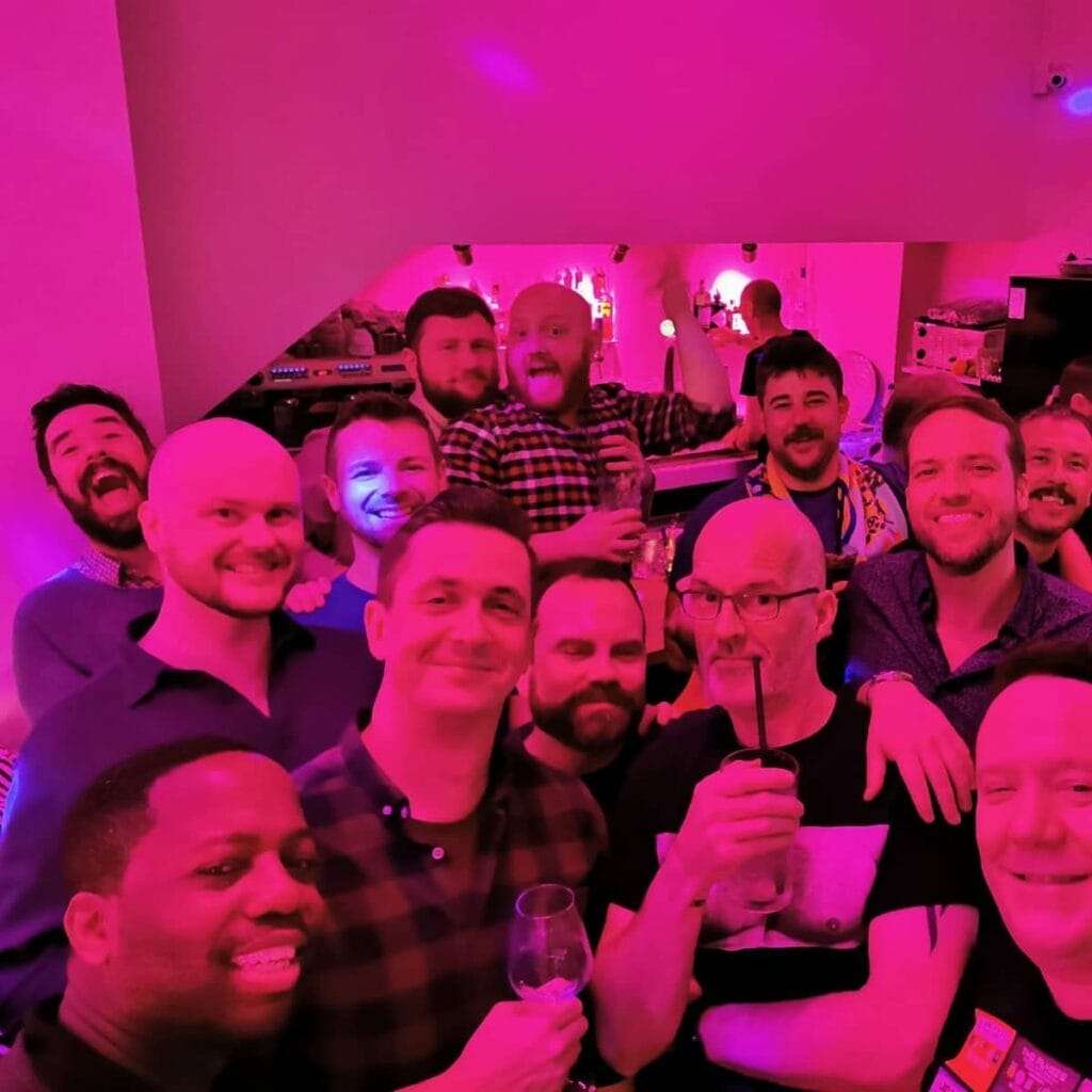 A group of men bathed in pink light in a bar in the centre of Amsterdam