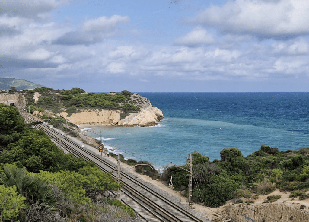 A view of the rail track with Platja de l'Home Mort in the background